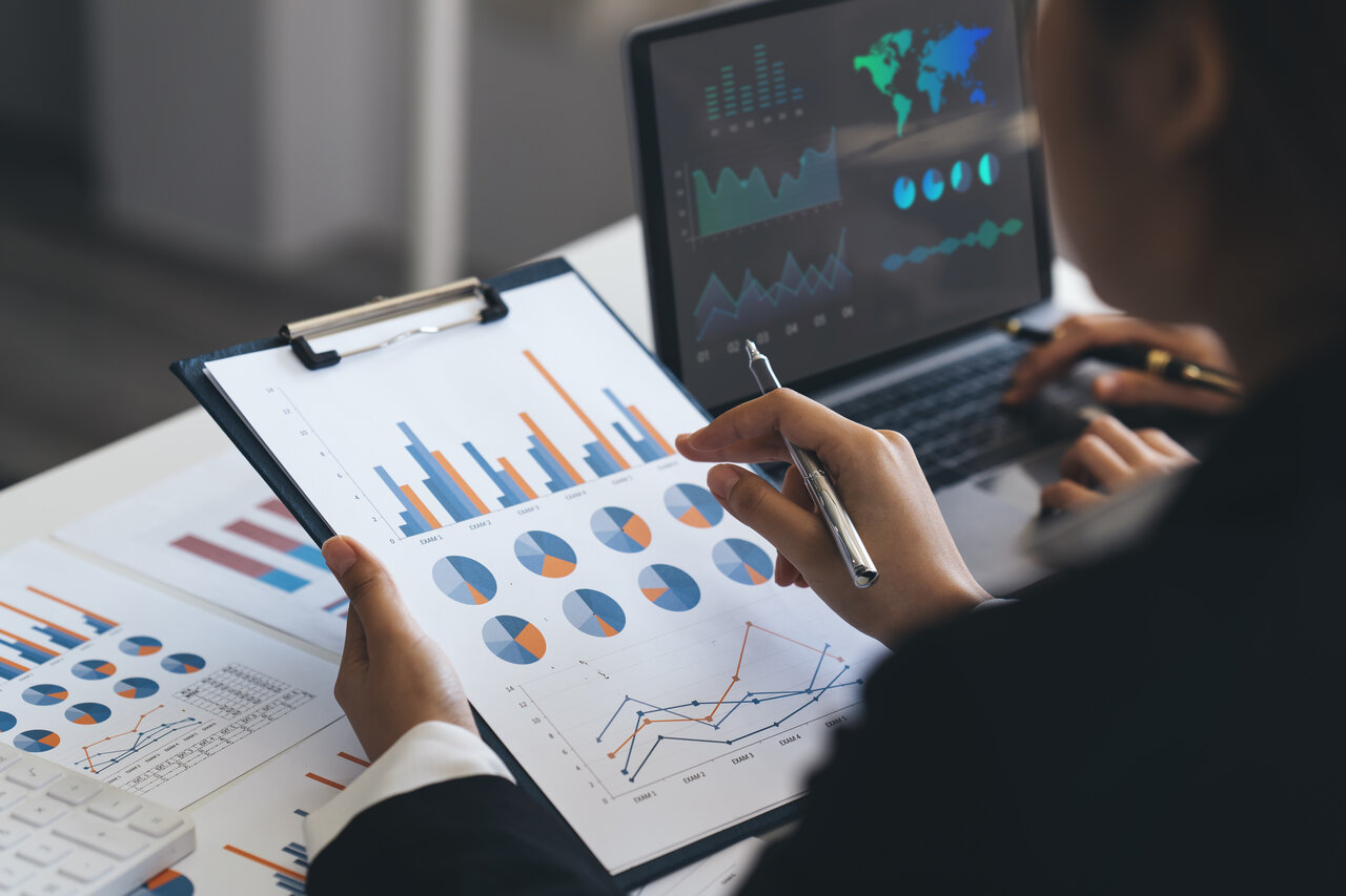 zwei Personen Analysieren Daten mit PC und Papier