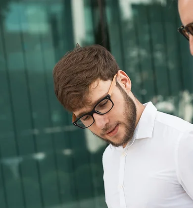Zwei Männer unterhalten sich vor der Glasfront eines Gebäudes