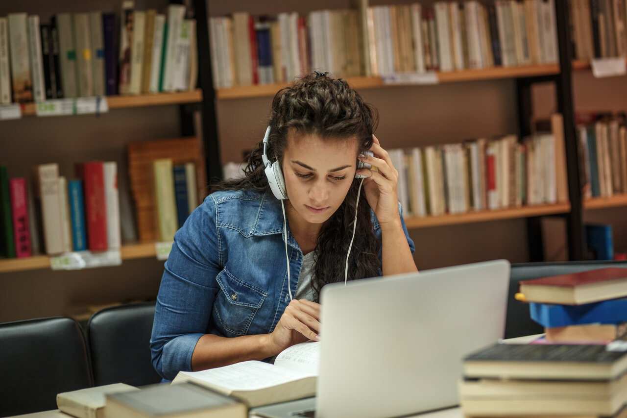 Eine Studentin sitzt in der Bibliothek an einem Laptop
