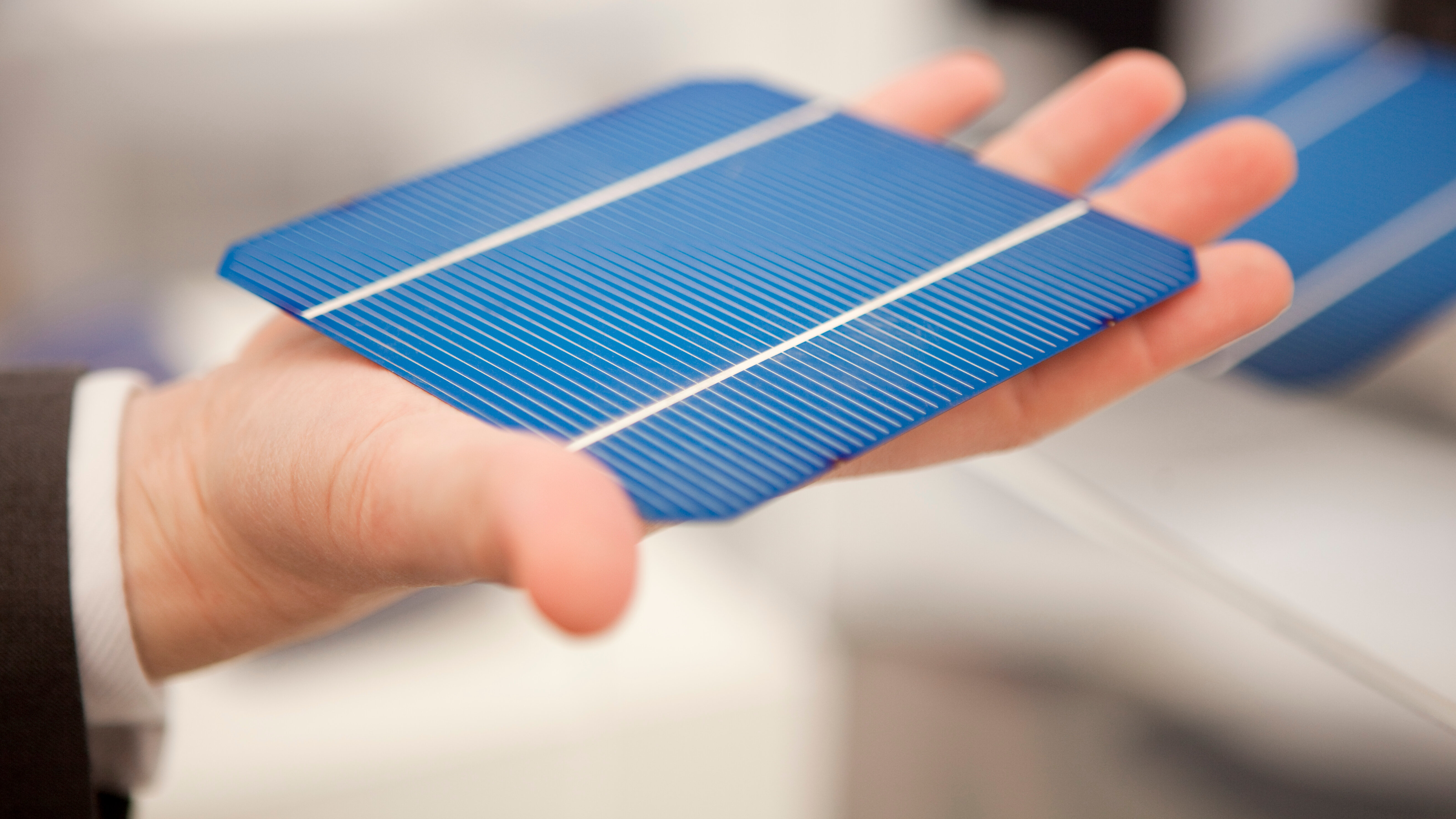 Eine Hand hält eine einzelne Photovoltaikzelle
