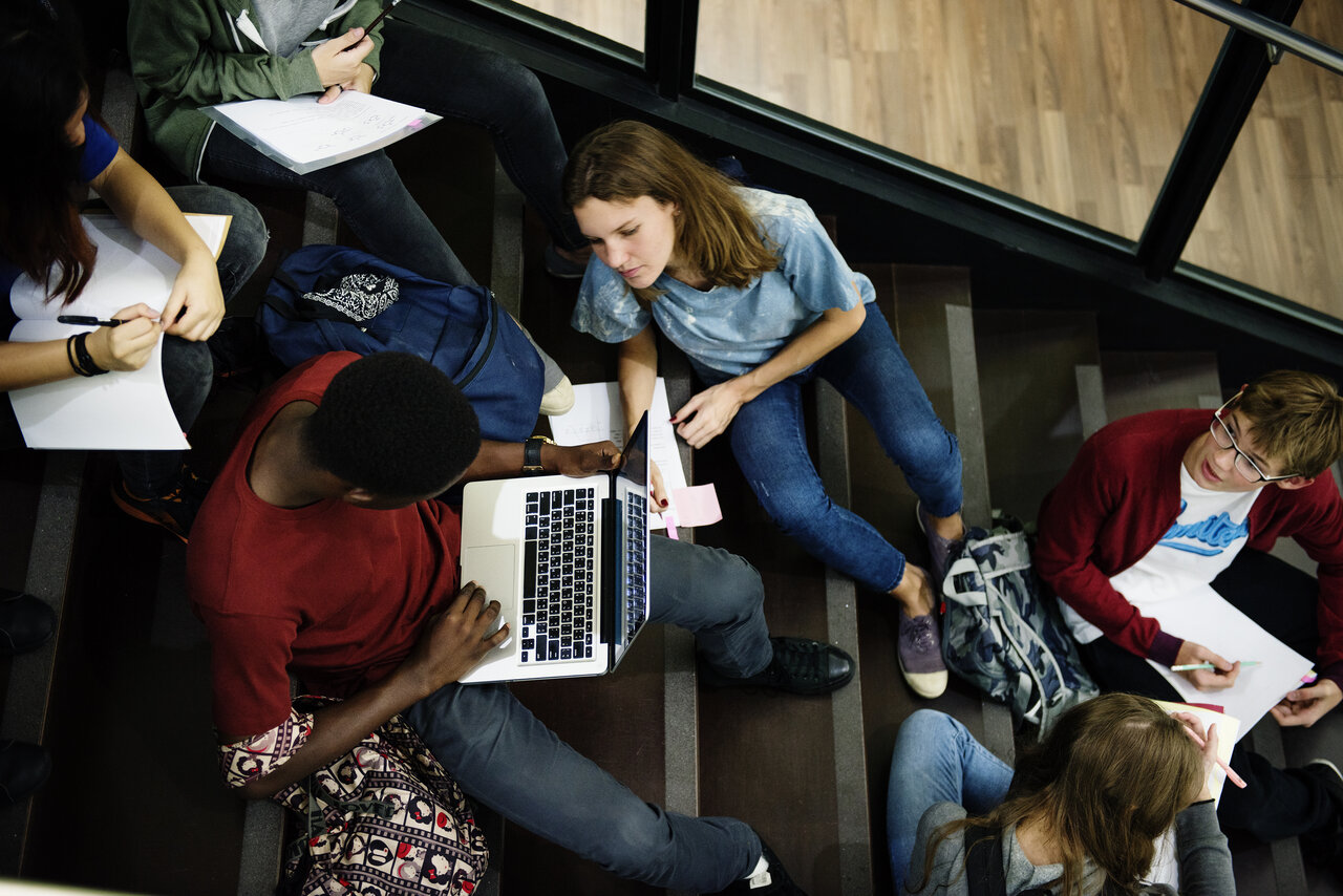 Ein Gruppe studenten sitztauf einer Treppe und arbeitet - draufsicht.