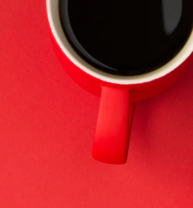 Bild einer Kaffetasse, eines Laptops und eines Notizbuchs auf einem roten Hintergrund