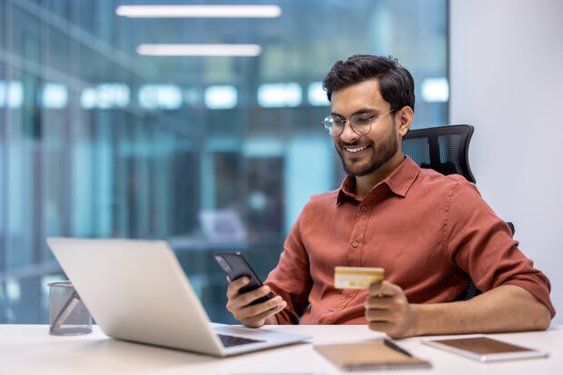 Mann in Büro mit Laptop und Handy
