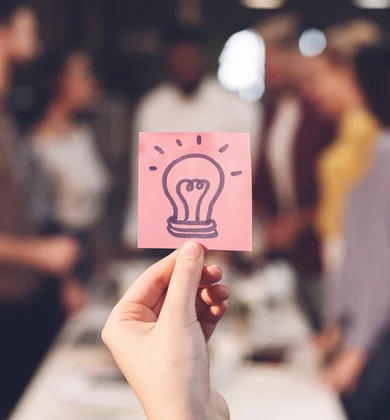 Postit mit Glühbirne, Personen im Hintergrund