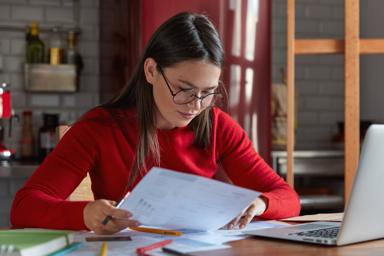 Frau in rotem Pullover lernt am Schreibtisch