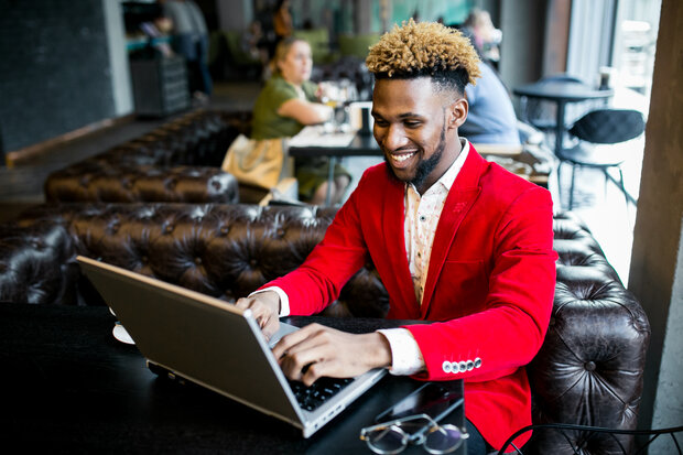 Mann sitzt an einem Laptop in einem Cafe